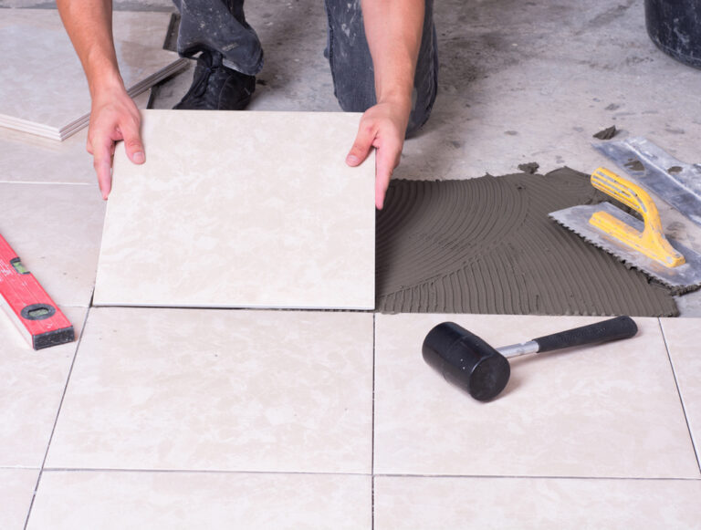 tiler installing ceramic tiles on floor