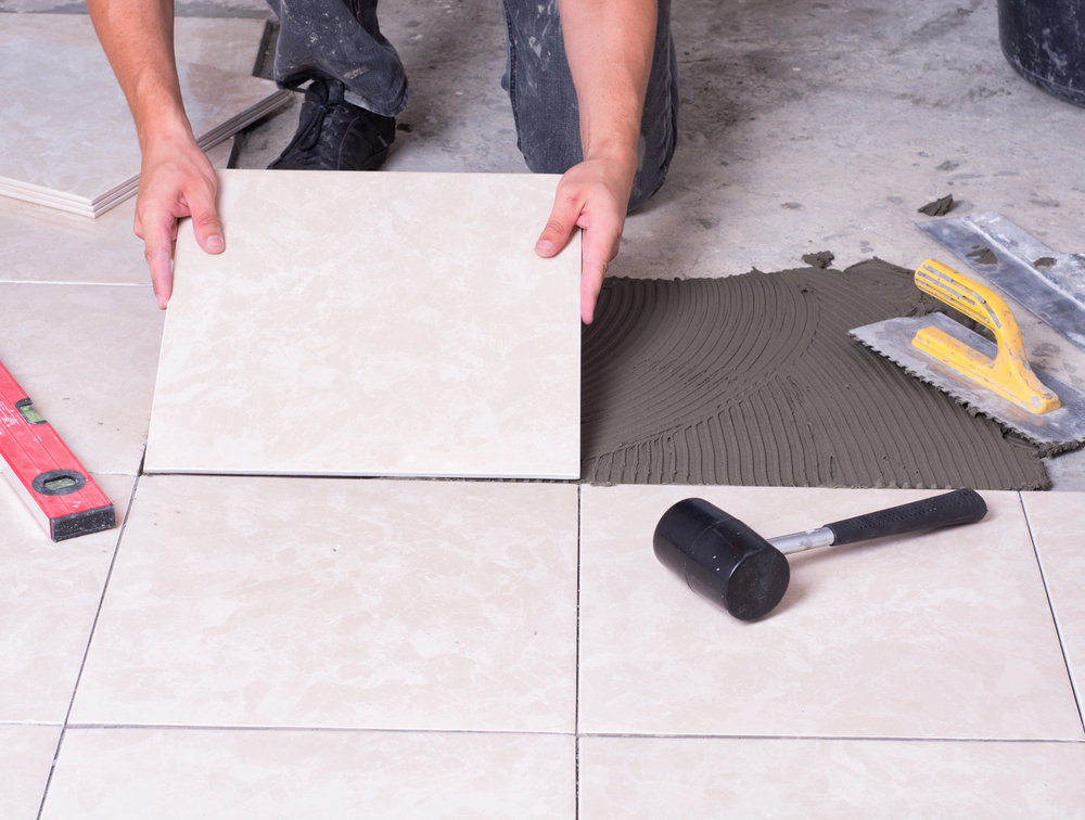 tiler installing ceramic tiles on floor